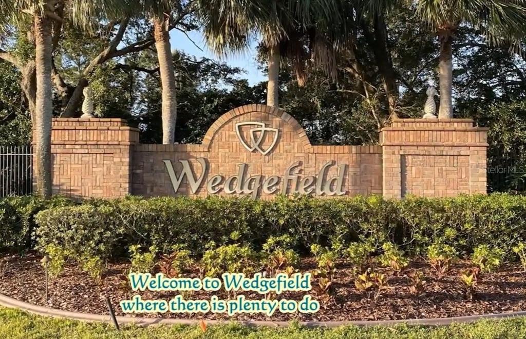 A brick monument sign with the name Wedgefield stands in front of trees and landscaping — Lot 32 STARRY STREET, ORLANDO, FL