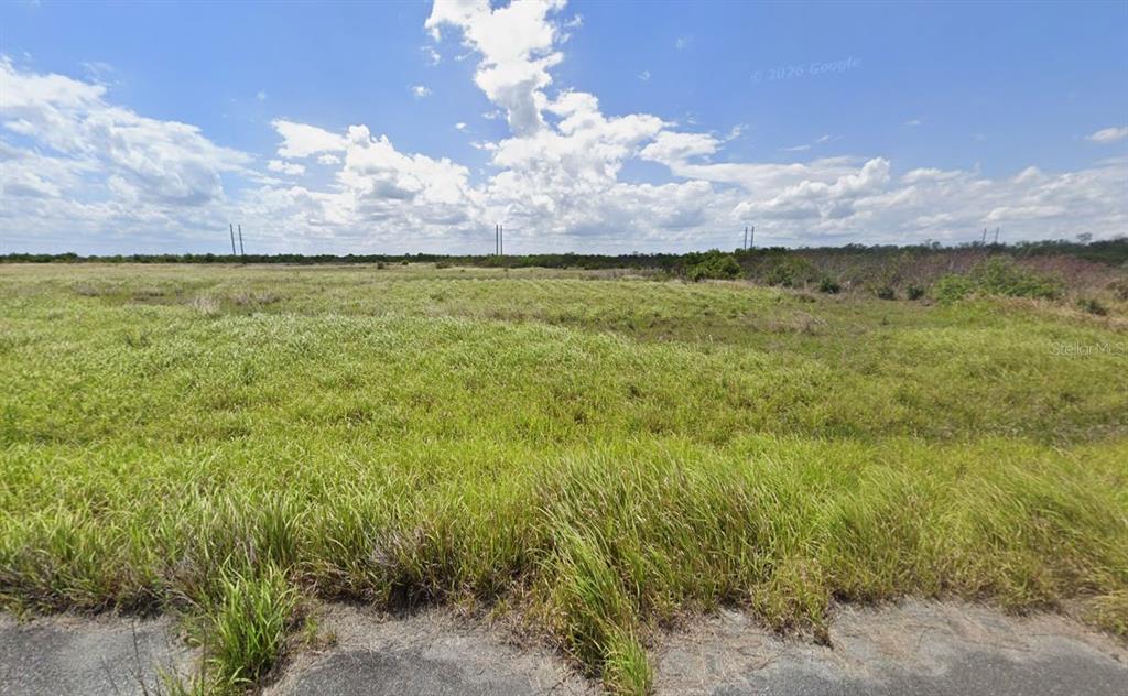 A wide, grassy, undeveloped field under a bright blue sky with scattered clouds — 2524 ADONIS AVENUE SW, PALM BAY, FL