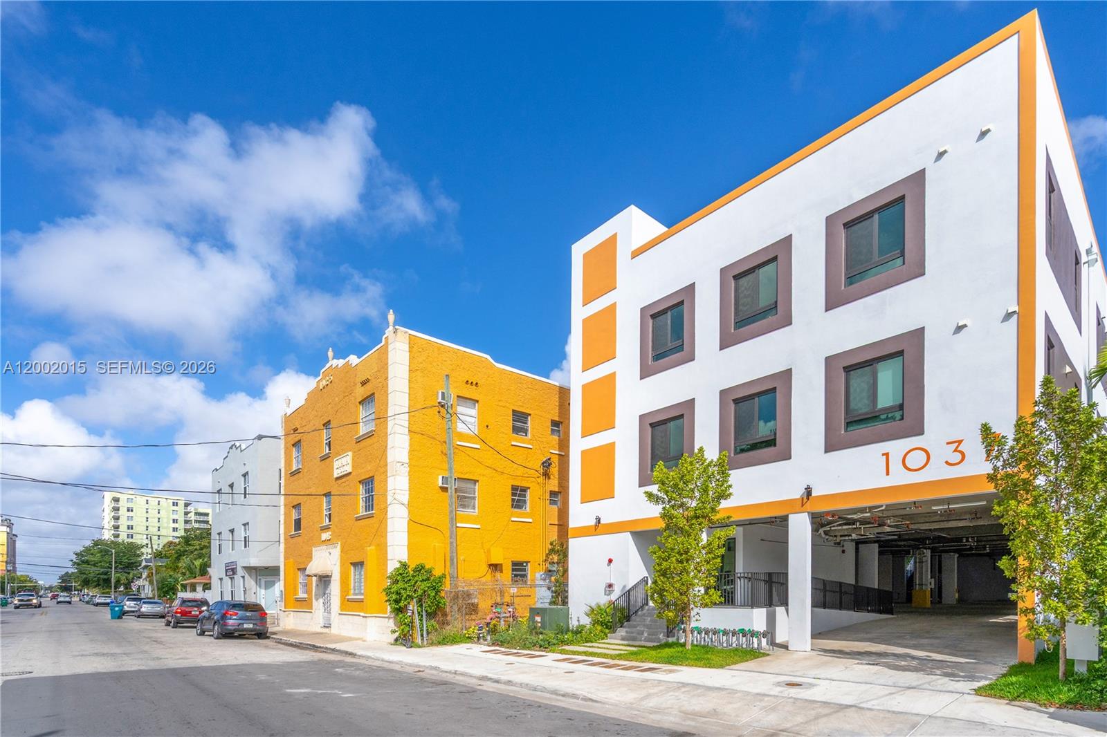 A modern white building with orange accents stands next to a historic yellow apartment building — 1037 NW 2nd St, Miami FL 33128, MIAMI, FL