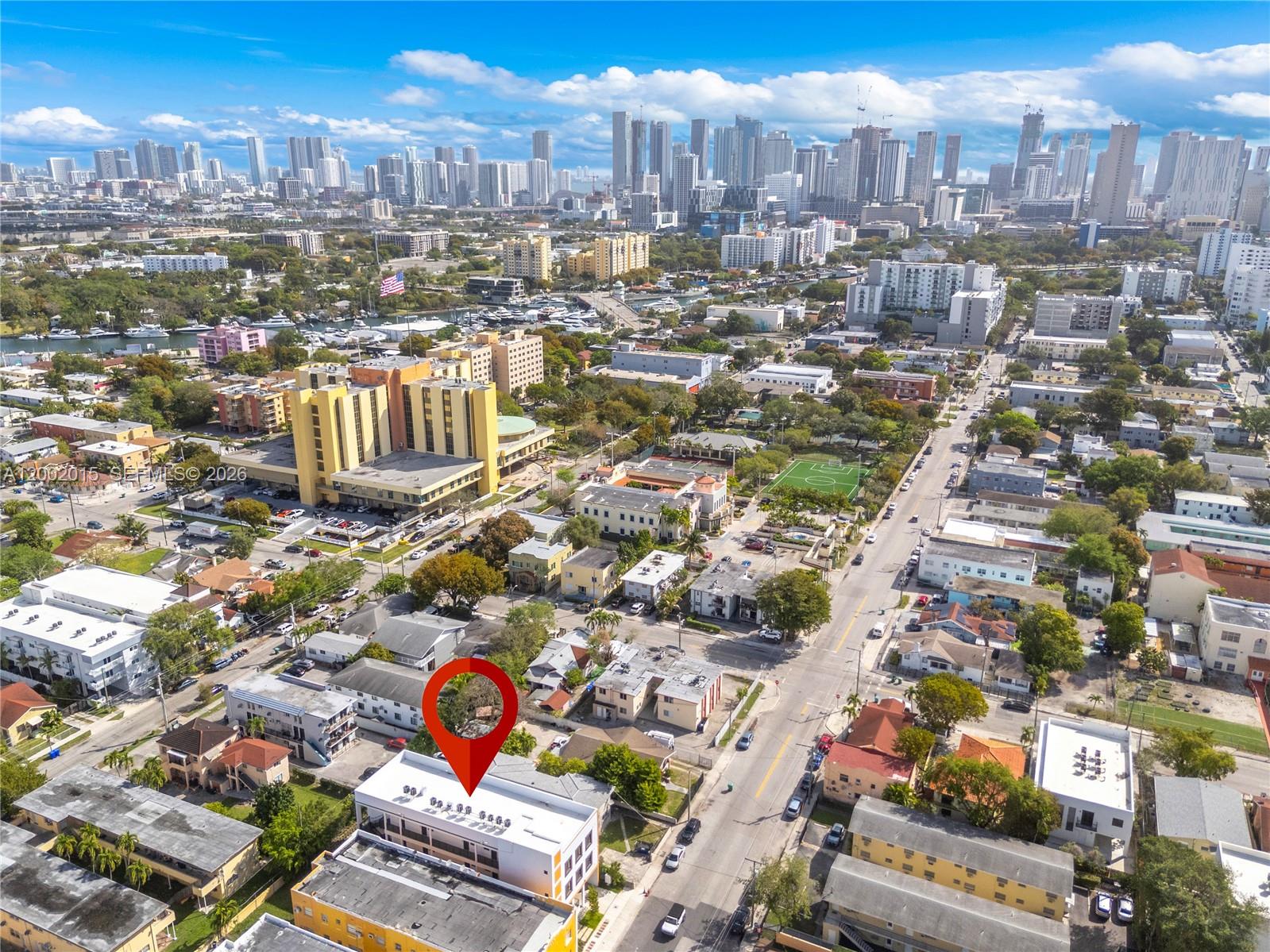 An aerial view shows a city neighborhood with a red location pin on a building — 1037 NW 2nd St, Miami FL 33128, MIAMI, FL