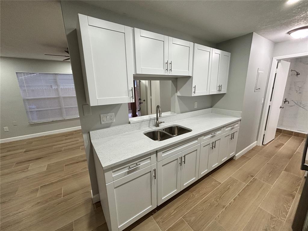 A kitchen features white shaker cabinets, light quartz countertops, and wood-look tile flooring — 14025 VILLAGE VIEW DRIVE, TAMPA, FL