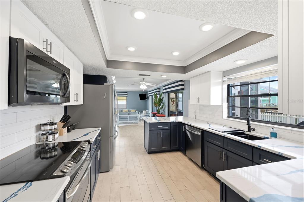 A modern kitchen features dark blue cabinets, white countertops, and stainless steel appliances — 4262 PARADISE CIRCLE, HERNANDO BEACH, FL