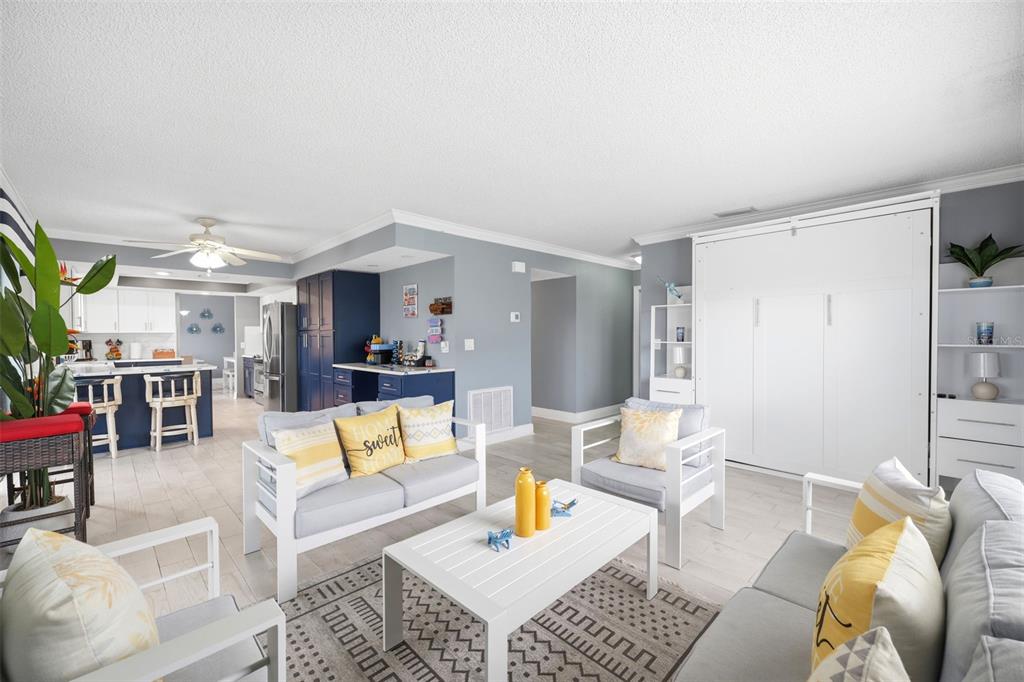 A living room with a Murphy bed, gray walls, tile floors, and an open kitchen — 4262 PARADISE CIRCLE, HERNANDO BEACH, FL