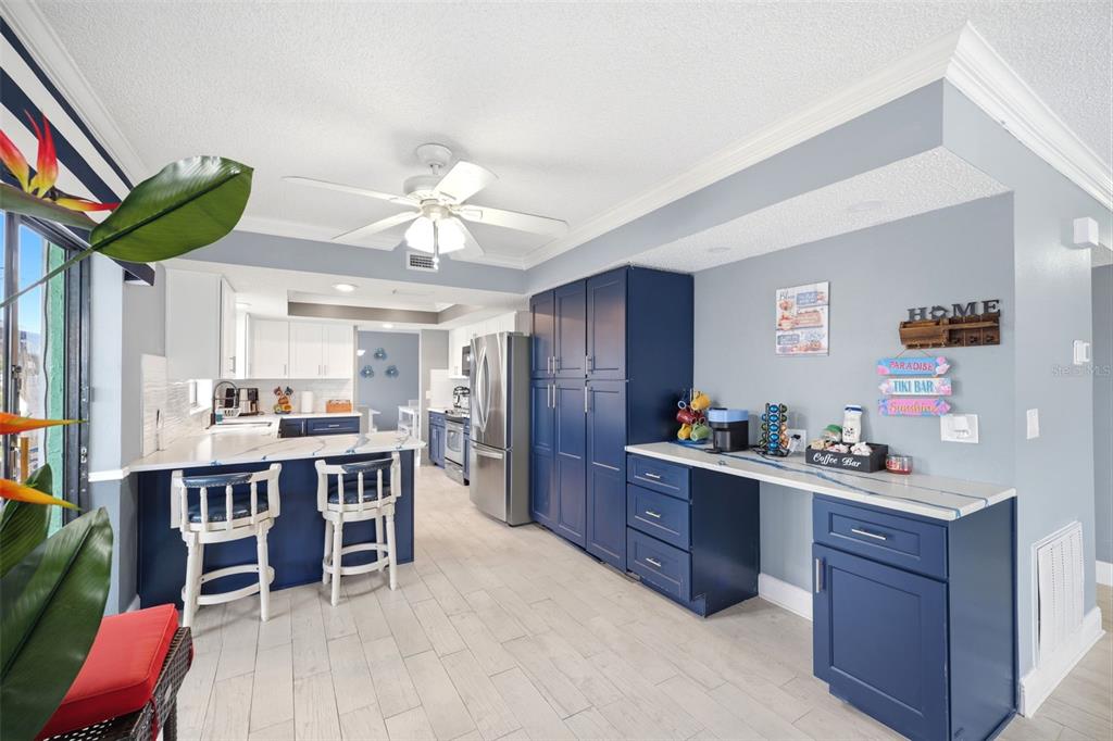 A kitchen features blue cabinetry, a breakfast bar with stools, and light-colored tile flooring — 4262 PARADISE CIRCLE, HERNANDO BEACH, FL