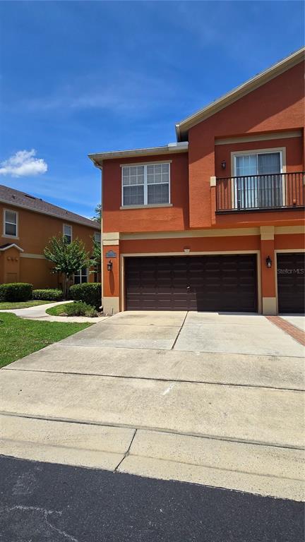 A two-story orange townhouse features a brown garage door and a second-floor balcony — 2921 PINE OAK TRAIL, SANFORD, FL