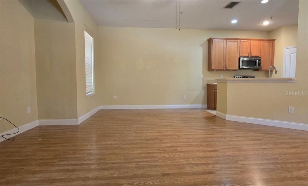 An open-concept living area features light-colored walls, wood-look flooring, and an adjacent kitchen — 2921 PINE OAK TRAIL, SANFORD, FL