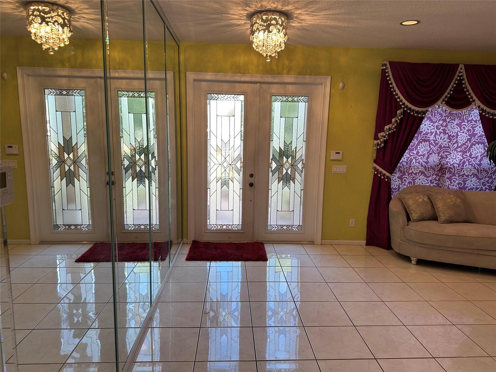 An entryway with tiled floors, mirrored walls, double glass-paneled doors, and a chandelier — 17488 SW 36th Street, Miramar FL 33029, MIRAMAR, FL