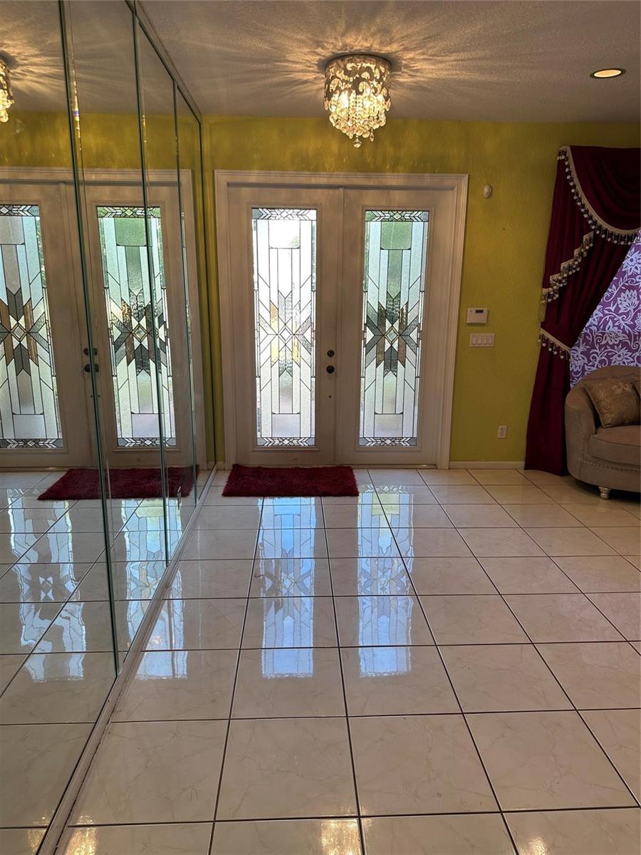 An entryway features white tile floors, a crystal chandelier, and double doors with decorative glass — 17488 SW 36th Street, Miramar FL 33029, MIRAMAR, FL