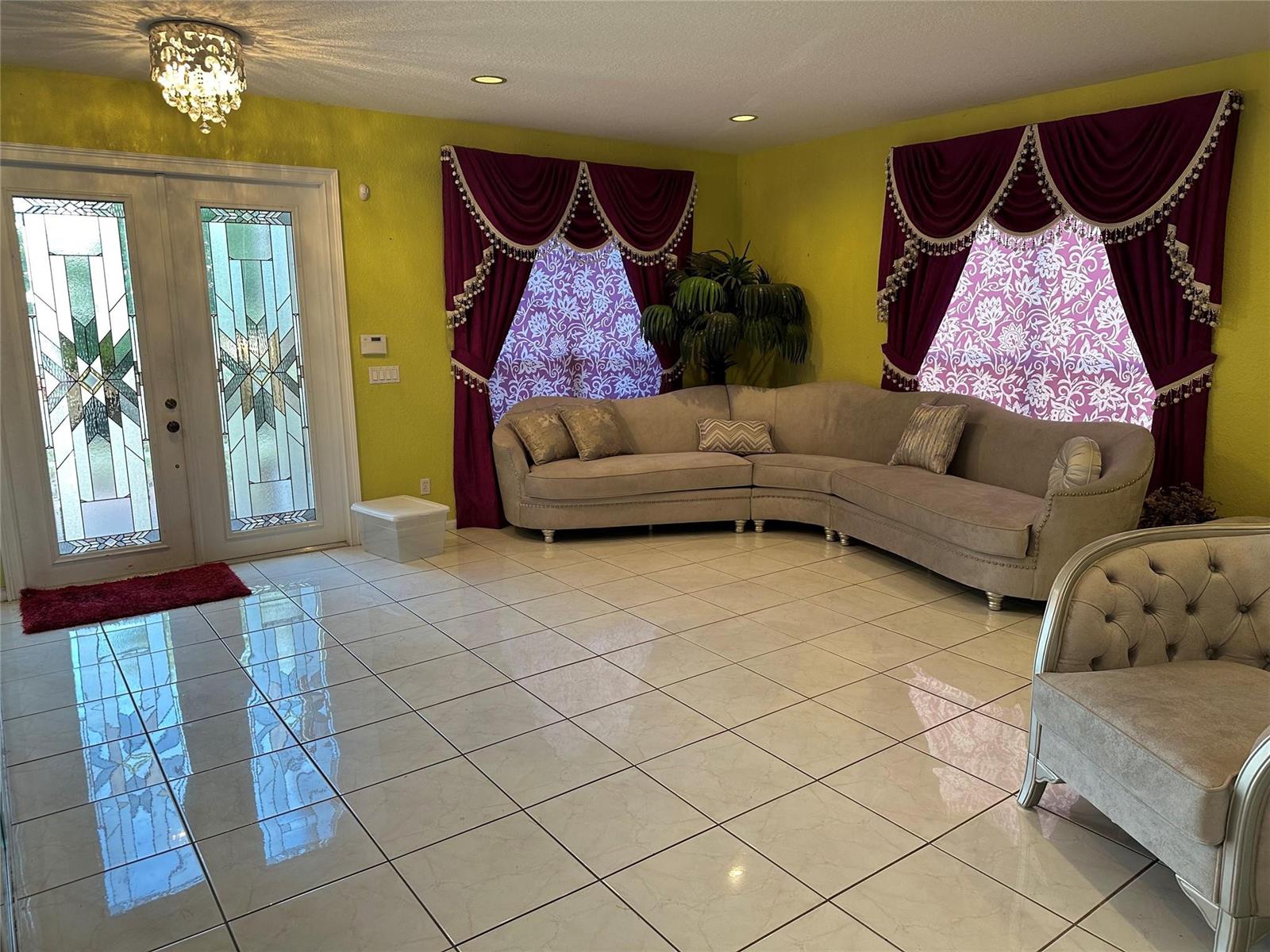 A living room features yellow walls, a curved sectional sofa, and ornate burgundy window treatments — 17488 SW 36th Street, Miramar FL 33029, MIRAMAR, FL