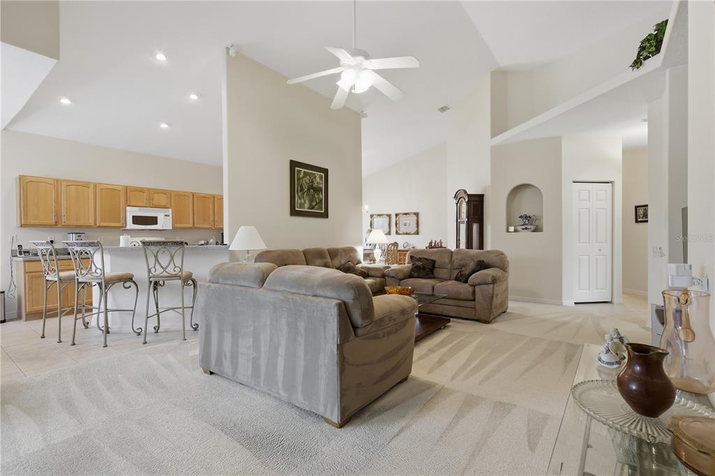 A living room with beige carpet and furniture opens to a kitchen with light wood cabinets — 14 CROSSLINK COURT, PALM COAST, FL