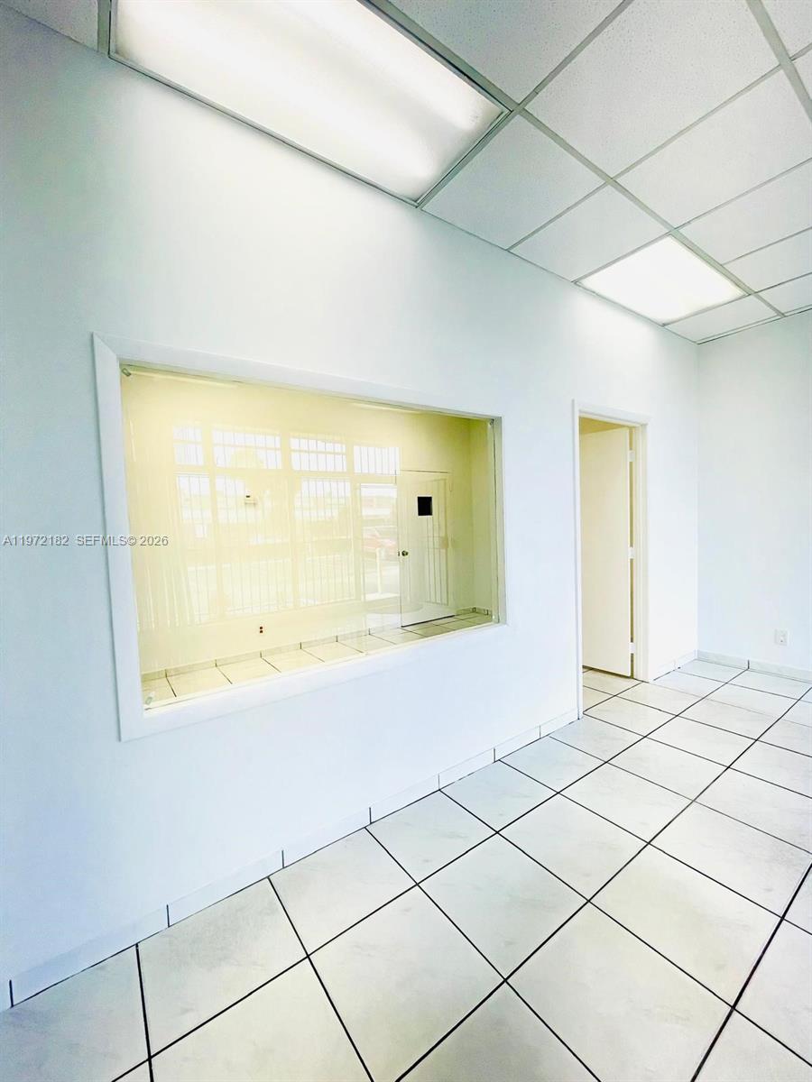 An interior office space features white walls, a large rectangular window, and tiled flooring — 3100 Milam Dairy Rd # 112, Miami FL 33122, MIAMI, FL