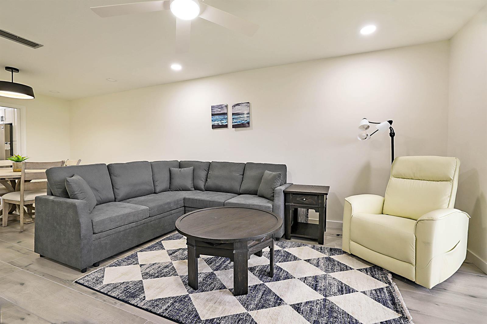 A living room features a gray sectional sofa, a round coffee table, and a recliner — 300 Intracoastal Place # 203, Jupiter FL 33469, JUPITER, FL