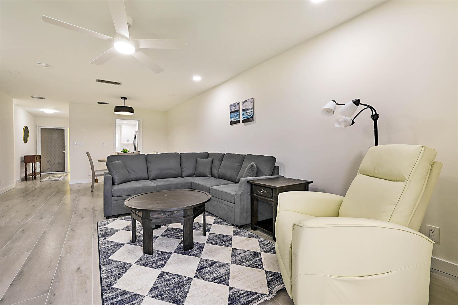 A living room features a gray sectional sofa, a round coffee table, and a cream recliner — 300 Intracoastal Place # 203, Jupiter FL 33469, JUPITER, FL
