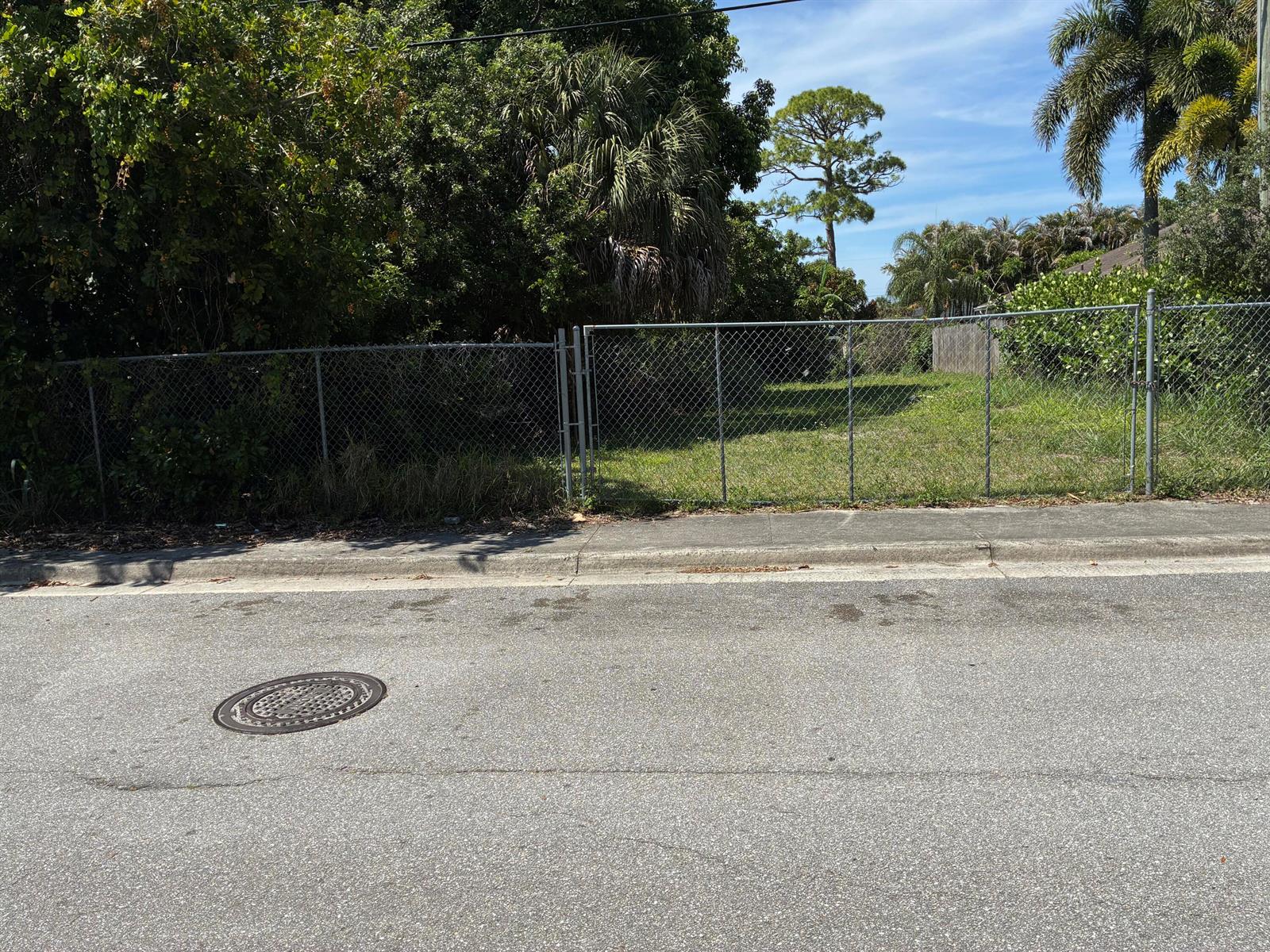 A chain-link fence encloses a vacant, grassy lot next to a paved street — 6755 1st Street, Jupiter FL 33458, JUPITER, FL