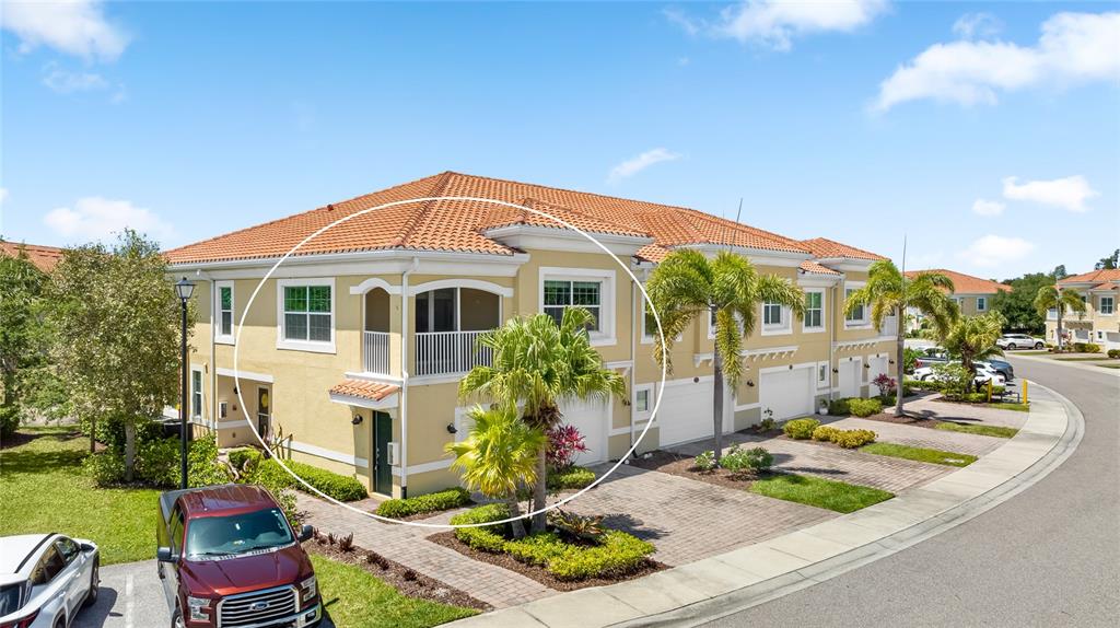 An exterior view of a two-story townhouse with a balcony and a tiled roof — 4271 EXPEDITION WAY UNIT 103, OSPREY, FL