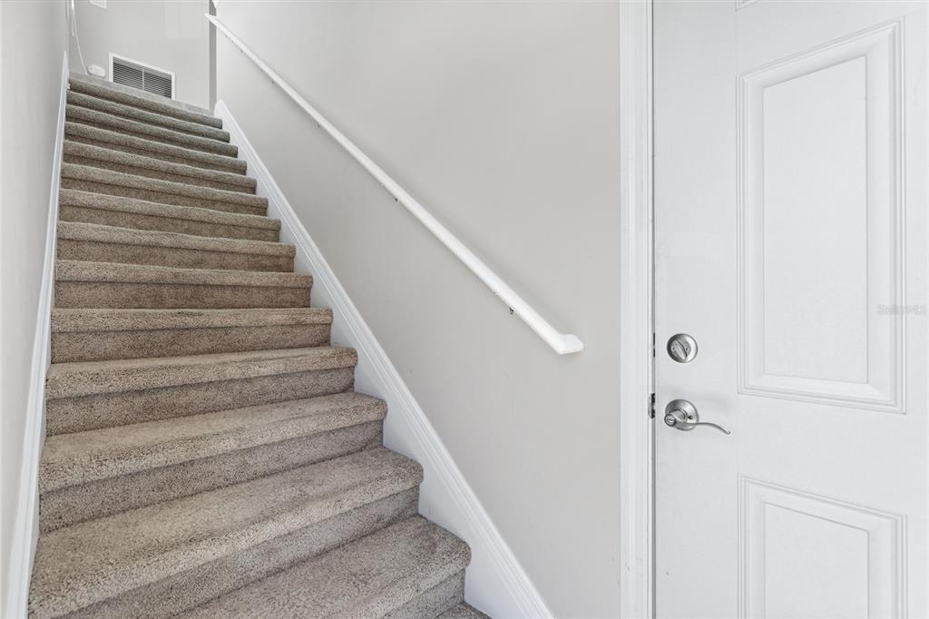 A carpeted staircase with a white handrail sits beside a white door — 4271 EXPEDITION WAY UNIT 103, OSPREY, FL