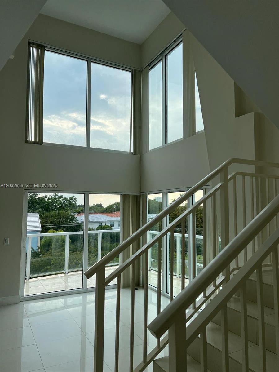 A two-story living area features floor-to-ceiling windows, white tile flooring, and a staircase — 1650 Brickell Ave # 206, Miami FL 33129, MIAMI, FL