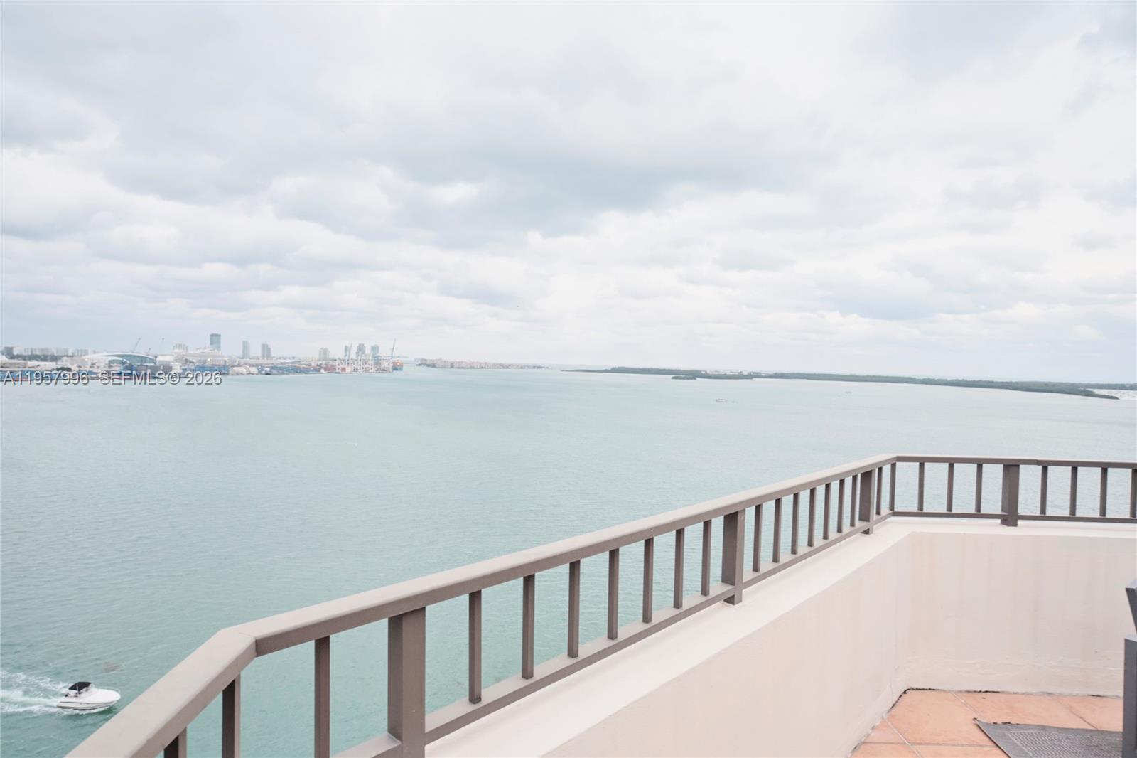 A modern kitchen island with a black sink overlooks a balcony with expansive water views — 520 Brickell Key Dr # A1904, Miami FL 33131, MIAMI, FL