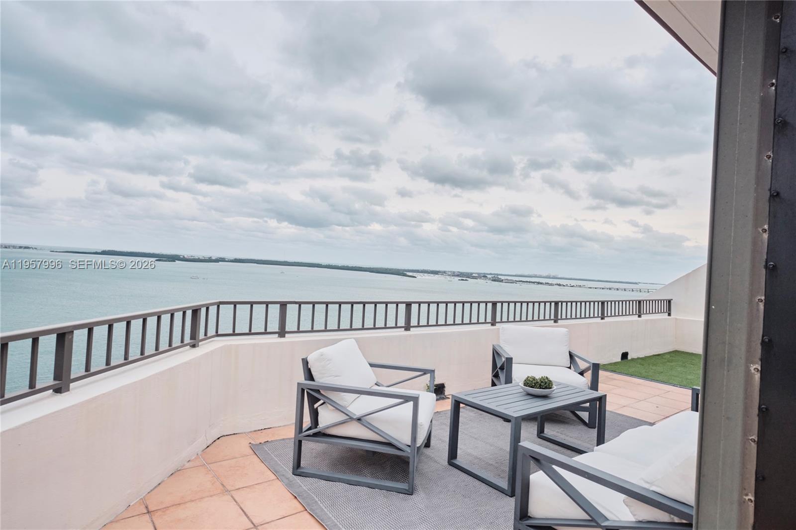 A balcony with tiled flooring, a single chair, and a view of the harbor — 520 Brickell Key Dr # A1904, Miami FL 33131, MIAMI, FL