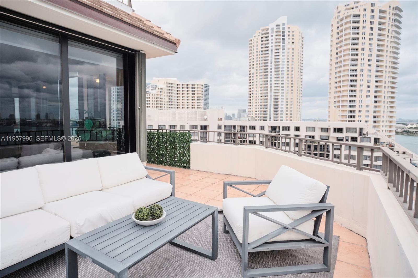 A spacious balcony features terracotta tile flooring, a metal railing, and panoramic water views — 520 Brickell Key Dr # A1904, Miami FL 33131, MIAMI, FL