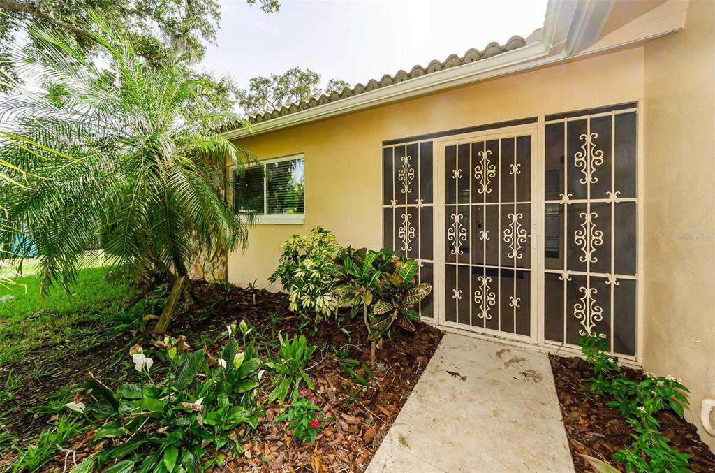 A front entryway features a beige door with side windows and a black floor mat — 1529 E DORCHESTER DRIVE, PALM HARBOR, FL