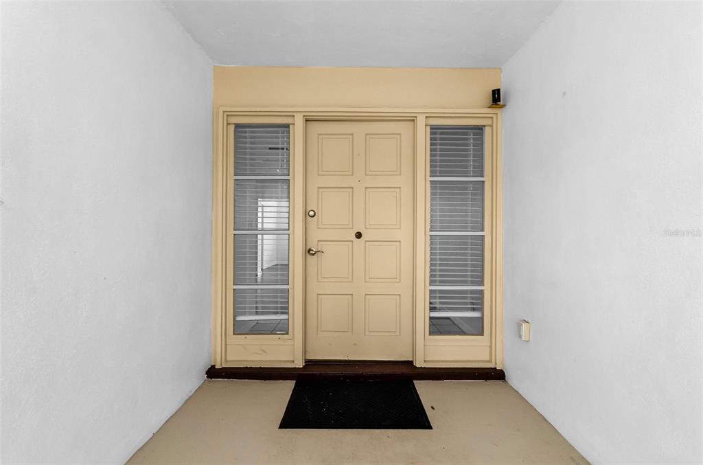 An entryway features a white paneled front door flanked by two windows with blinds — 1529 E DORCHESTER DRIVE, PALM HARBOR, FL