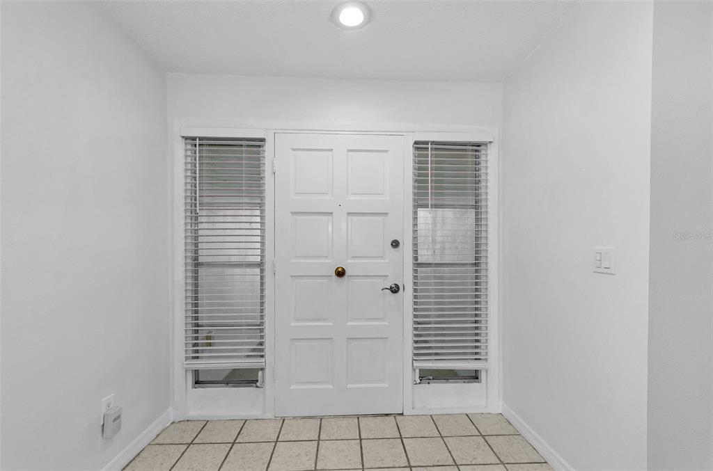 A living room with wood-look flooring, white walls, track lighting, and a view into another room — 1529 E DORCHESTER DRIVE, PALM HARBOR, FL