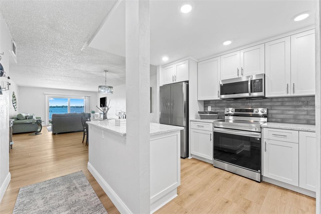 A kitchen with white cabinets and stainless steel appliances opens to a living area with water — 3606 S PENINSULA DRIVE UNIT 103, PORT ORANGE, FL