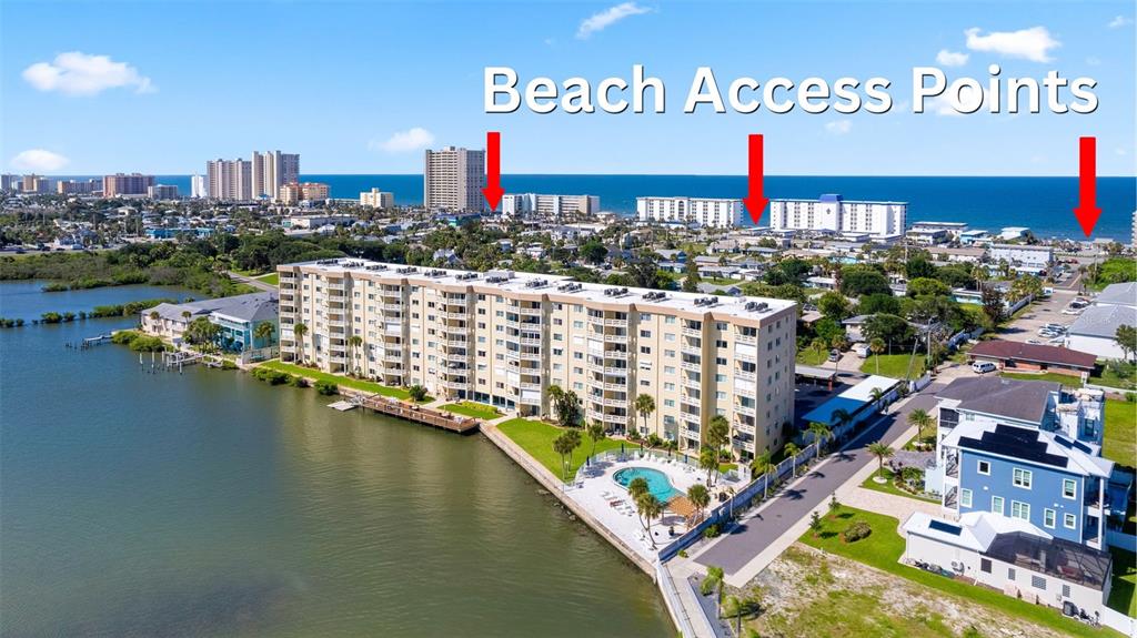 An aerial view shows a waterfront apartment building with a pool, nearby beach, and ocean — 3606 S PENINSULA DRIVE UNIT 103, PORT ORANGE, FL