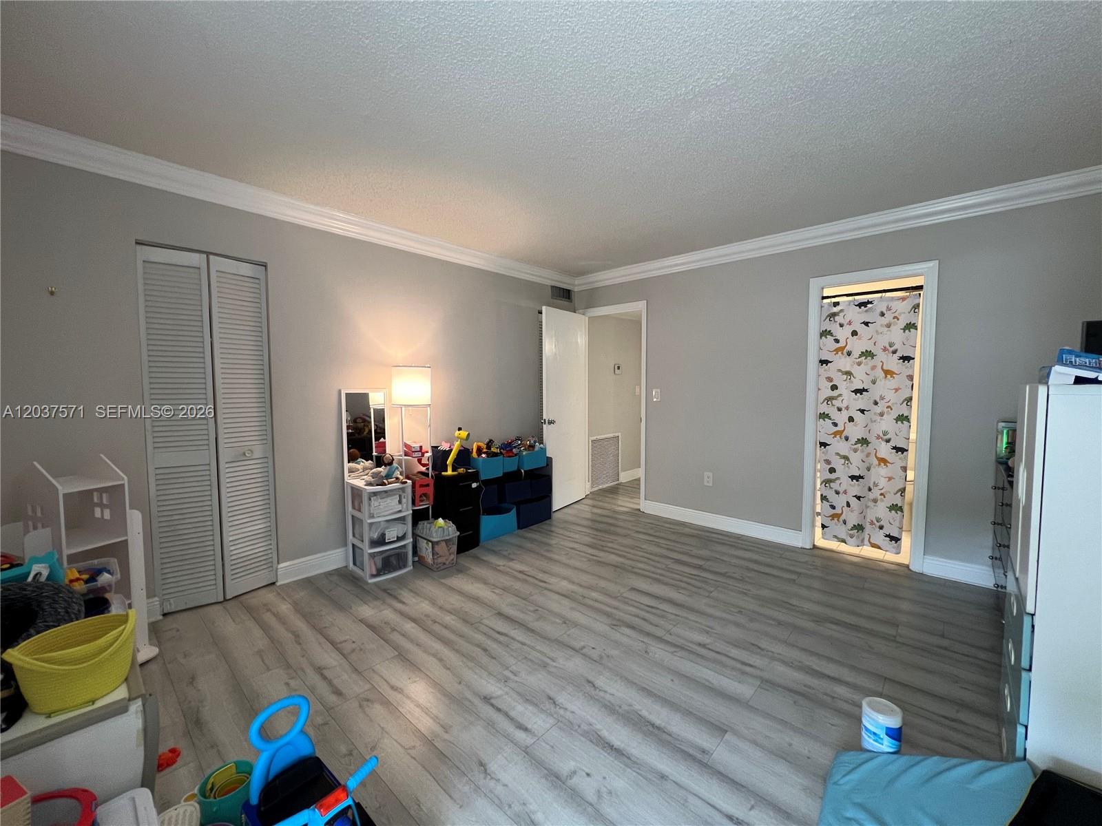 A bedroom with gray walls, light wood-look flooring, a closet, and an attached bathroom — 6886 N Kendall Dr # D407, Pinecrest FL 33156, PINECREST, FL