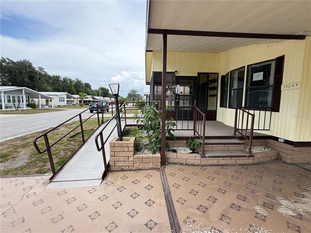 The exterior of a mobile home features a metal ramp, stairs, and a covered patio — 35044 MCCULLOUGHS LEAP, ZEPHYRHILLS, FL