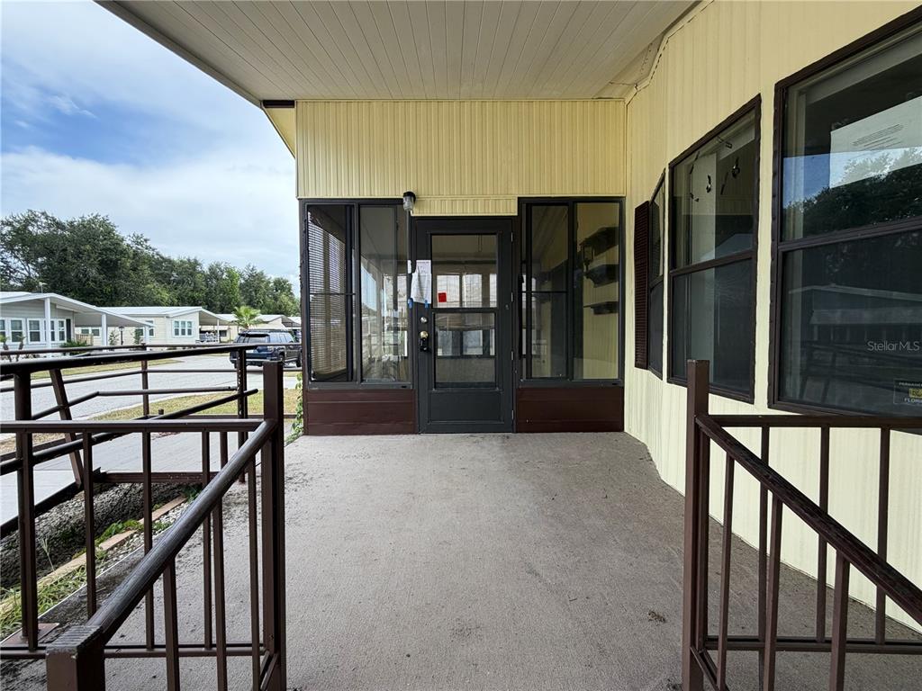 A covered concrete porch with metal railings leads to a glass-paneled front door — 35044 MCCULLOUGHS LEAP, ZEPHYRHILLS, FL