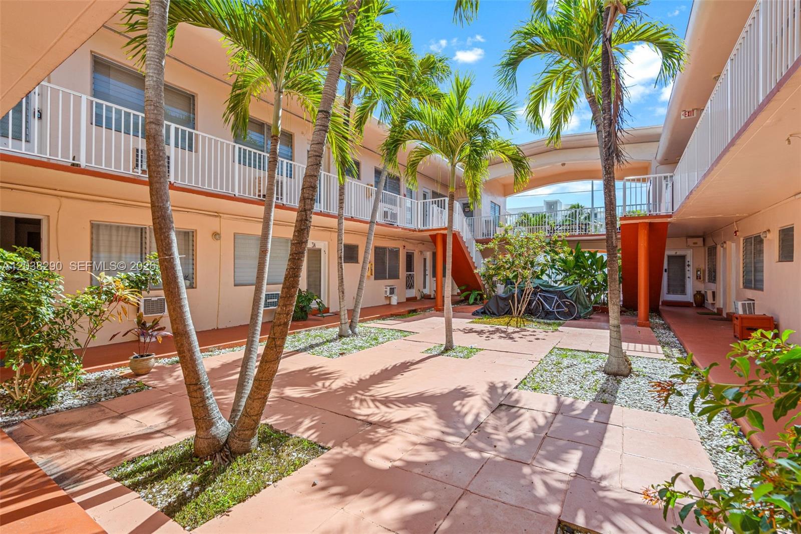 An outdoor courtyard features palm trees, paved walkways, and two-story apartment balconies — 7840 Harding Ave # 3, Miami Beach FL 33141, MIAMI BEACH, FL