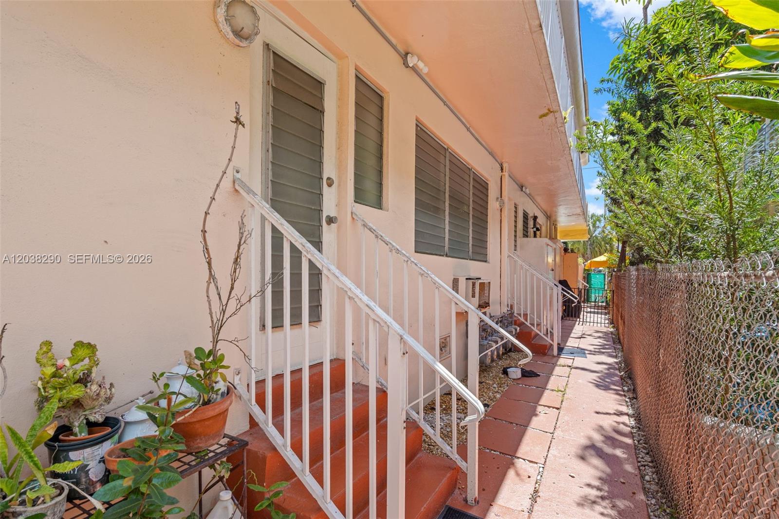 An exterior view shows a peach-colored building with stairs leading to a doorway — 7840 Harding Ave # 3, Miami Beach FL 33141, MIAMI BEACH, FL