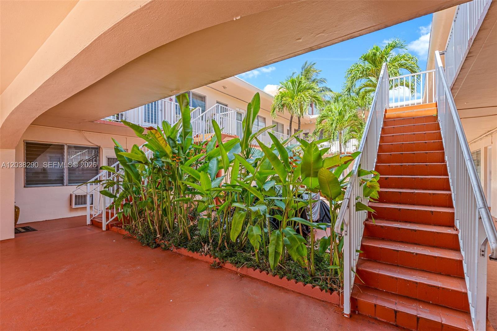 An outdoor courtyard features a staircase, tropical plants, and a covered walkway — 7840 Harding Ave # 3, Miami Beach FL 33141, MIAMI BEACH, FL