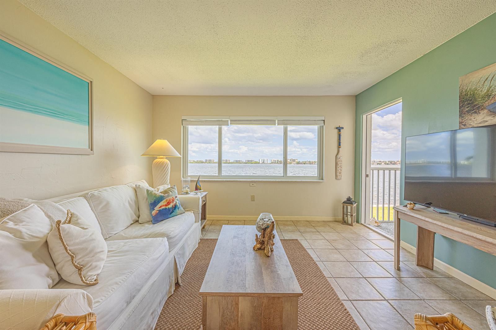 A living room with a white sofa, coffee table, television, and a view of water — 1516 S Lakeside Drive # 203, FL 33460, FL
