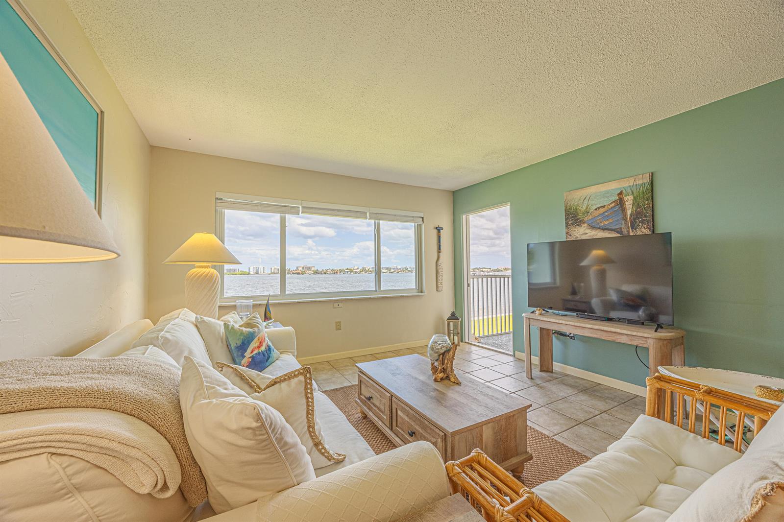 A living room with a white sofa, coffee table, television, and a view of the water — 1516 S Lakeside Drive # 203, FL 33460, FL