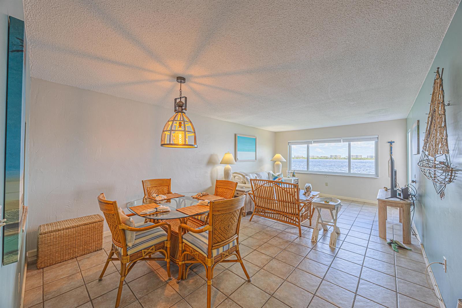 A dining area and living room with rattan furniture, tile floors, and a waterfront view — 1516 S Lakeside Drive # 203, FL 33460, FL