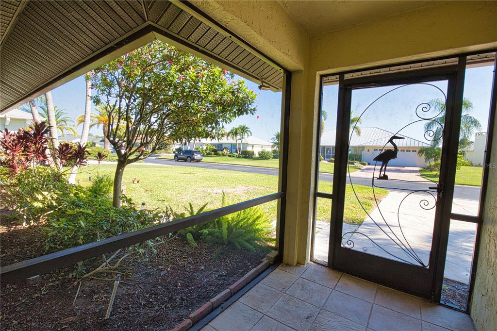 A screened-in porch with tiled flooring overlooks a residential street and a landscaped yard — 902 PINEHURST LANE, VENICE, FL