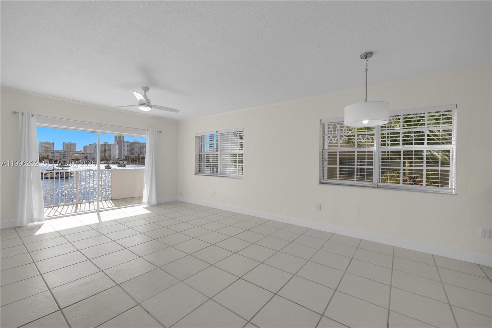 An empty room with light tile flooring, a ceiling fan, and a balcony overlooking water — 462 Golden Isles Dr # 210, Hallandale Beach FL 33009, HALLANDALE BEACH, FL