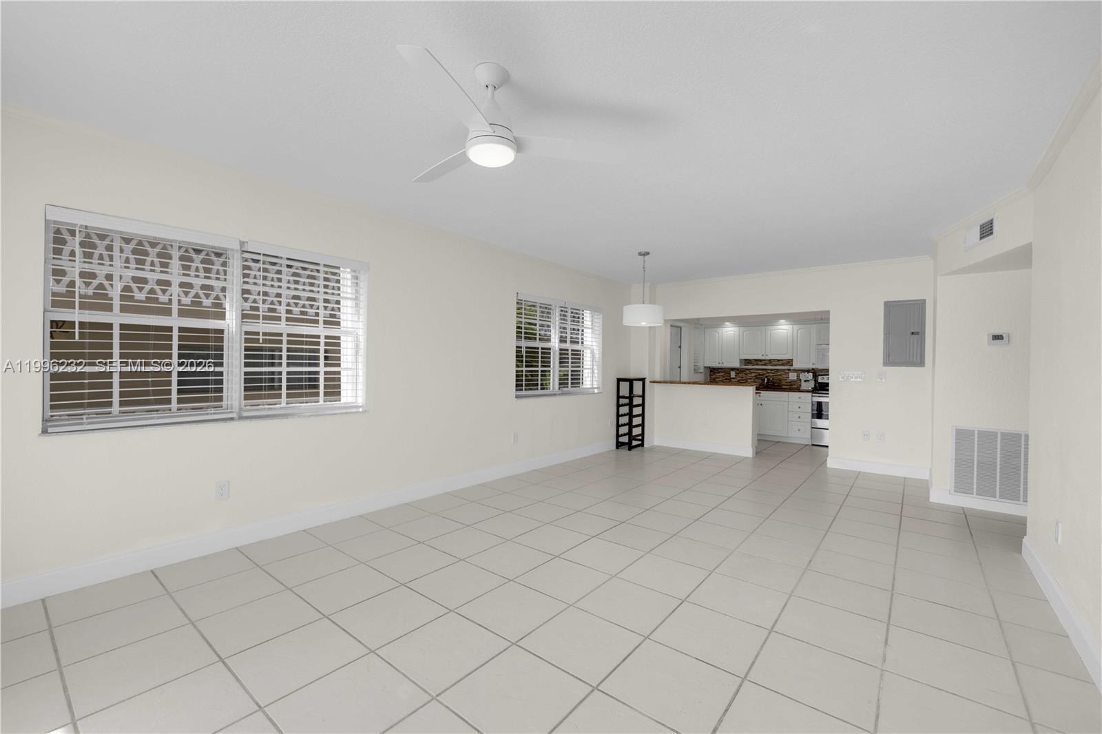 A bright, open-concept living and dining area features white tile flooring and a ceiling fan — 462 Golden Isles Dr # 210, Hallandale Beach FL 33009, HALLANDALE BEACH, FL
