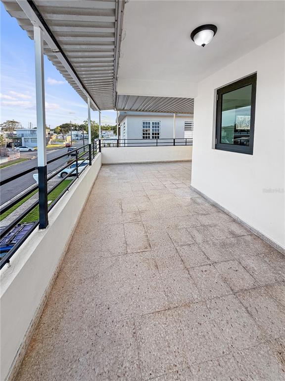A covered outdoor balcony features tiled flooring, a black metal railing, and a white wall — 234 234 UNIT HH16 - B, CAROLINA, PR