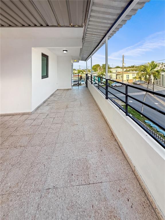 A long, covered balcony features light-colored tiled flooring and a black metal railing — 234 234 UNIT HH16 - B, CAROLINA, PR