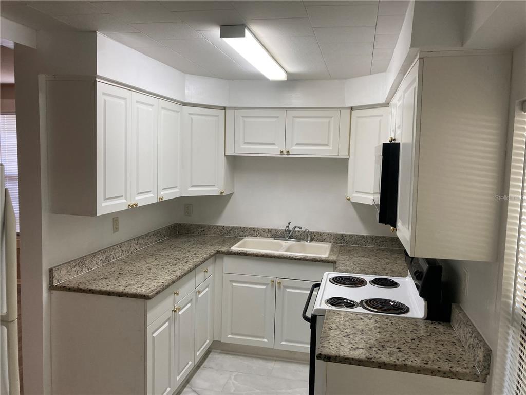 A kitchen features white cabinets, speckled laminate countertops, a double sink, and an electric stove — 2004 2ND AVE UNIT 2, BRADENTON, FL