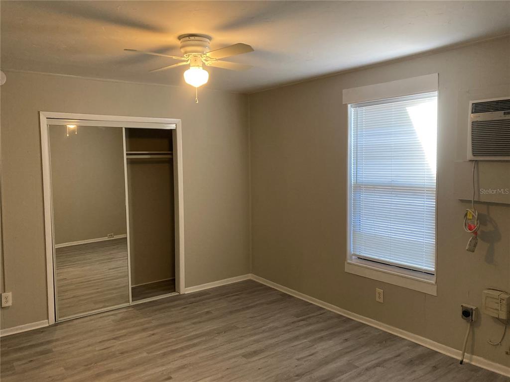 A bedroom with light gray walls, wood-look flooring, a ceiling fan, and a mirrored closet — 2004 2ND AVE UNIT 2, BRADENTON, FL
