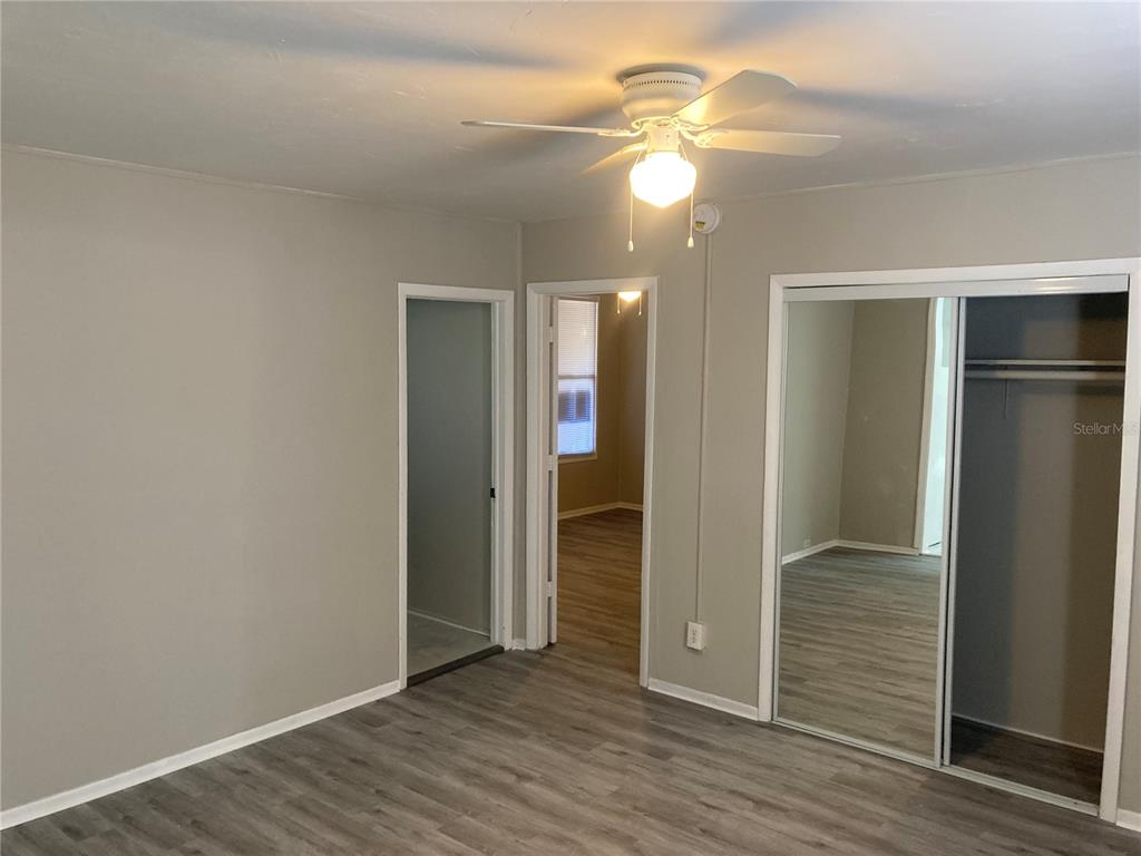 A bedroom features gray walls, wood-look flooring, a ceiling fan, and a mirrored closet — 2004 2ND AVE UNIT 2, BRADENTON, FL