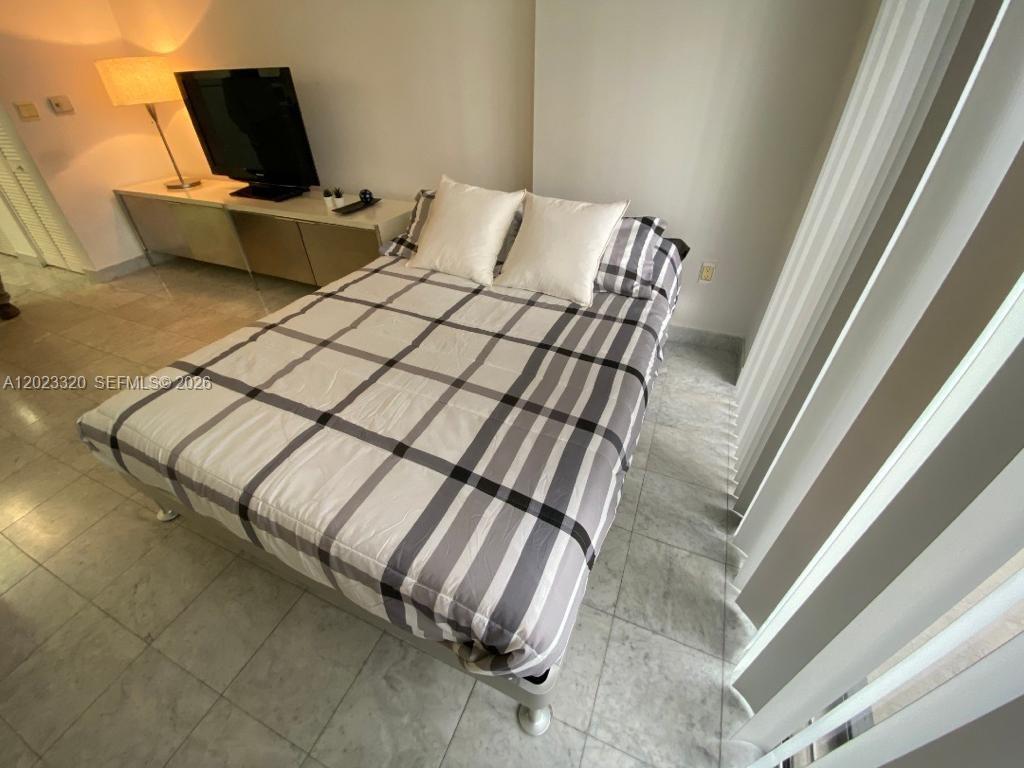 A bedroom features a bed with a plaid comforter, tile flooring, and a television console — 540 Brickell Key Dr # 913, Miami FL 33131, MIAMI, FL
