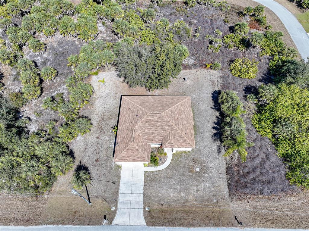 An aerial view shows a single-story house with a brown roof surrounded by native vegetation — 13452 CEDAR CITY AVENUE, PORT CHARLOTTE, FL