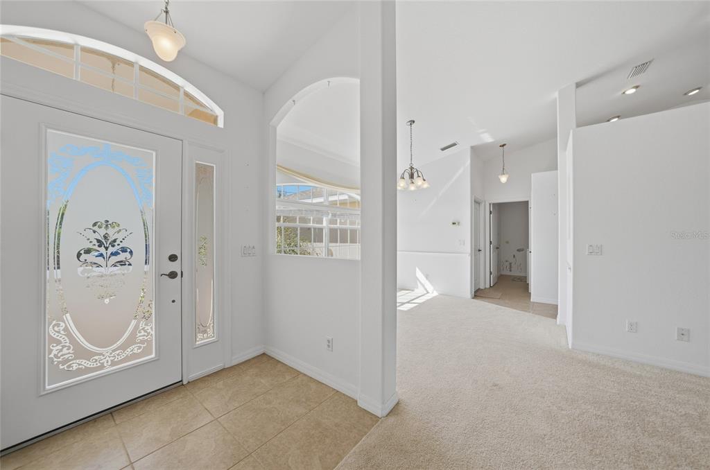 An entryway with tile flooring leads into a carpeted living area with high ceilings — 13452 CEDAR CITY AVENUE, PORT CHARLOTTE, FL