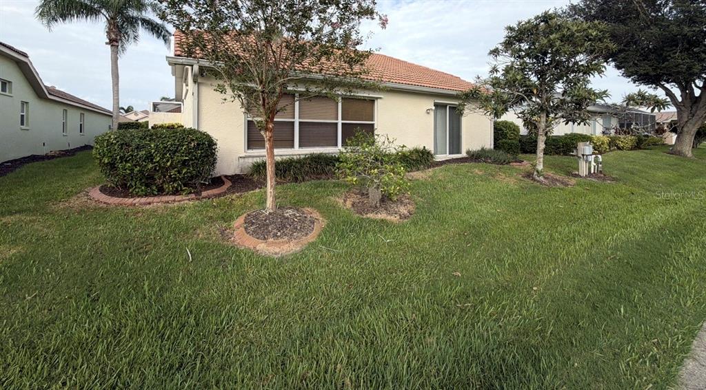 The exterior of a single-story house features a tiled roof, stucco walls, and a lawn — 229 VENICE PALMS BOULEVARD, VENICE, FL